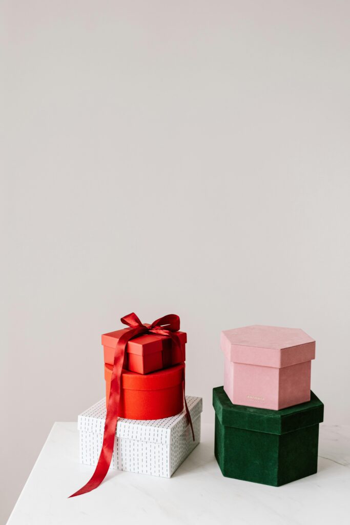 Different forms and colors and textures gift boxes placed on each other on white table against gray background